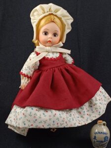 Madame Alexander doll in floral dress with red apron